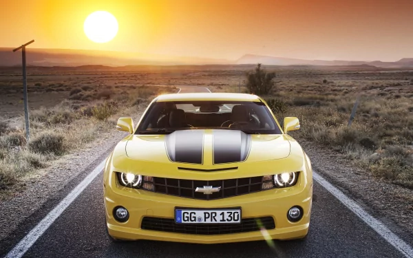 HD desktop wallpaper featuring a yellow Chevrolet Camaro with black racing stripes parked on an open road at sunset.