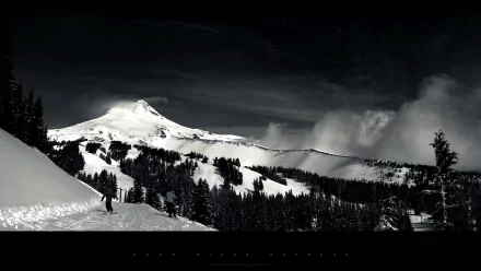 HD PC desktop wallpaper: nature mountain scene in monochrome — snow-capped peak, forested slopes, lone walker on a snowy ridge beneath dramatic clouds.