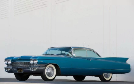 HD PC desktop wallpaper of a teal 1960 Cadillac Sixty-Two Coupe vehicle against a pale wall, showcasing chrome grille, sweeping tailfins and whitewall tires.