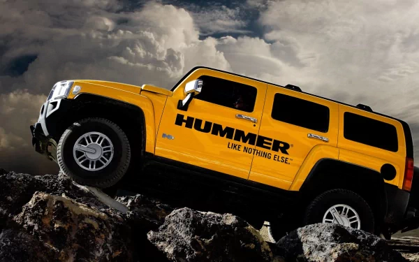 Yellow Hummer climbing rocky terrain beneath dramatic clouds — HD PC desktop wallpaper and background.