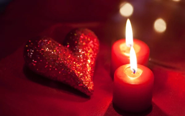 A glittery red heart and two glowing red candles create a warm Valentine's Day scene in this 4K Ultra HD desktop wallpaper.