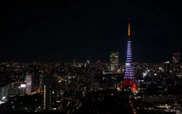 Night view of Tokyo Tower illuminated in red and white, standing tall amid the cityscape of Tokyo, Japan.