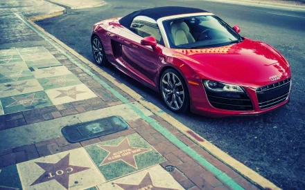 A red Audi R8 V10 Spyder convertible parked beside a sidewalk with Hollywood Walk of Fame stars, captured as an HD PC desktop wallpaper and background.