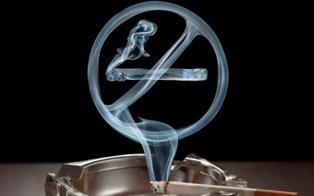 Artistic HD PC wallpaper showing a lit cigarette in an ashtray with smoke forming a translucent no smoking symbol against a black background.