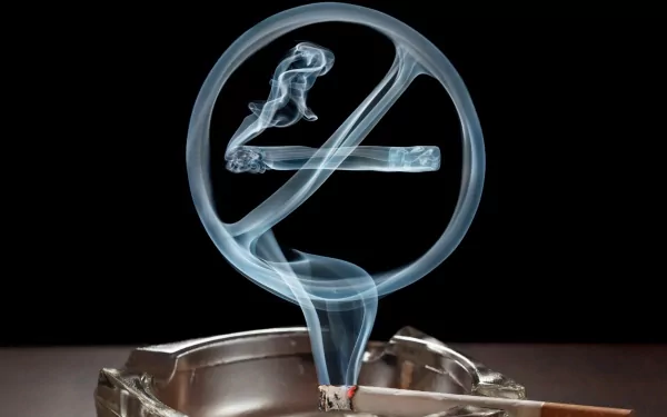 Artistic HD PC wallpaper showing a lit cigarette in an ashtray with smoke forming a translucent no smoking symbol against a black background.