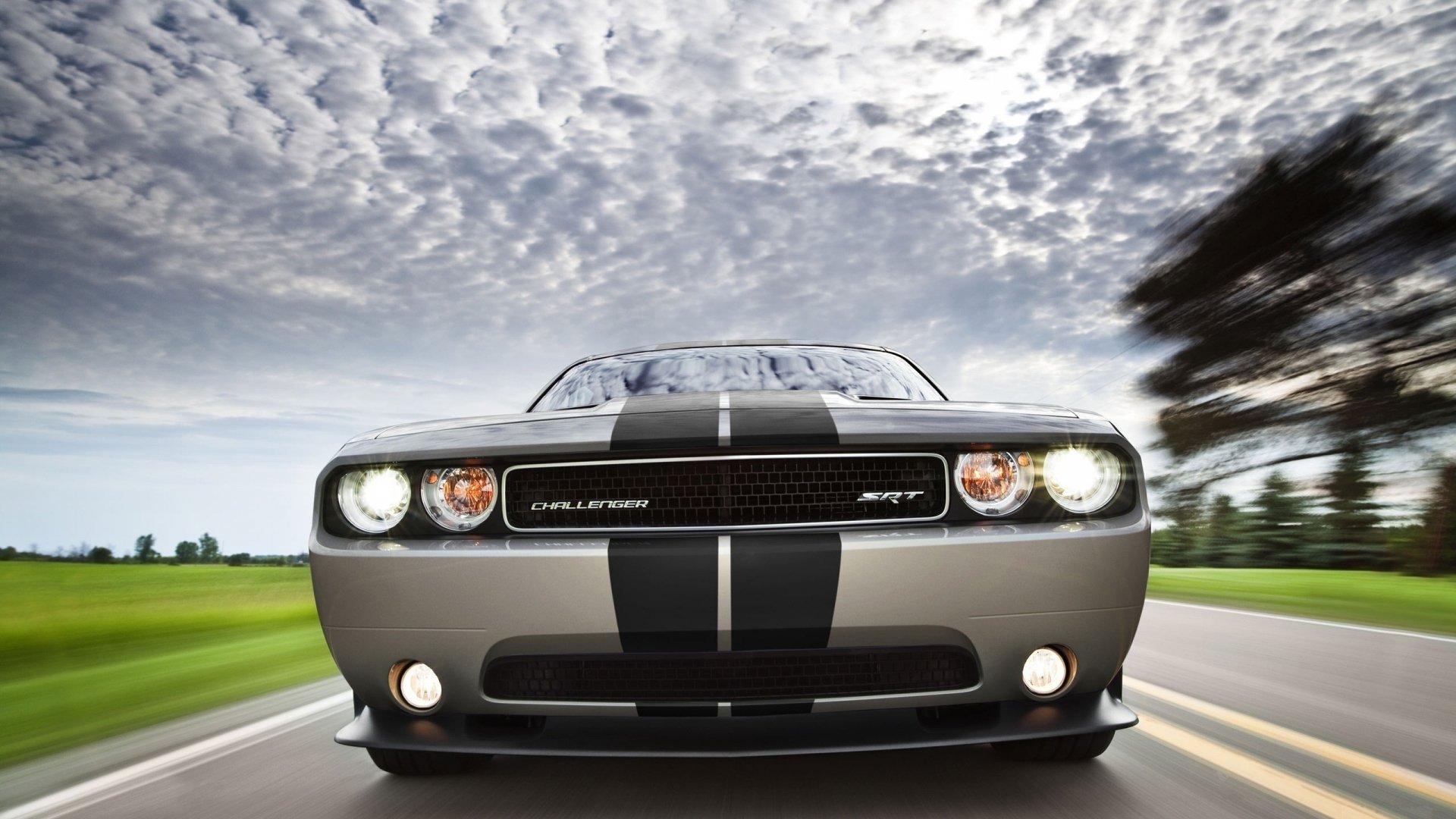 Front view of a Dodge Challenger SRT driving on a road under a cloudy sky, captured in HD for a PC desktop wallpaper and background.