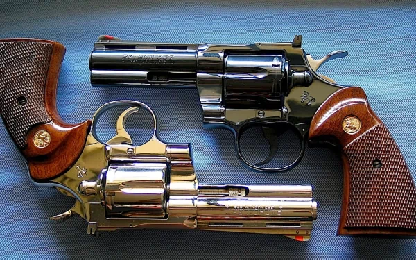HD desktop wallpaper featuring a close-up of two man-made Colt Python revolvers with detailed wooden grips and metallic finishes.