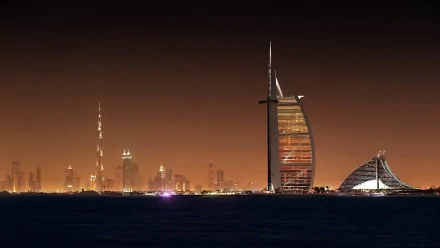 HD desktop wallpaper showcasing Dubai’s iconic man-made skyline at night, featuring the Burj Al Arab and illuminated cityscape in the background.
