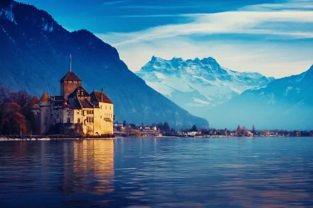 Serene view of Château de Chillon in Veytaux, Switzerland, surrounded by tranquil waters and majestic mountains, showcasing the beauty of this man-made landmark.