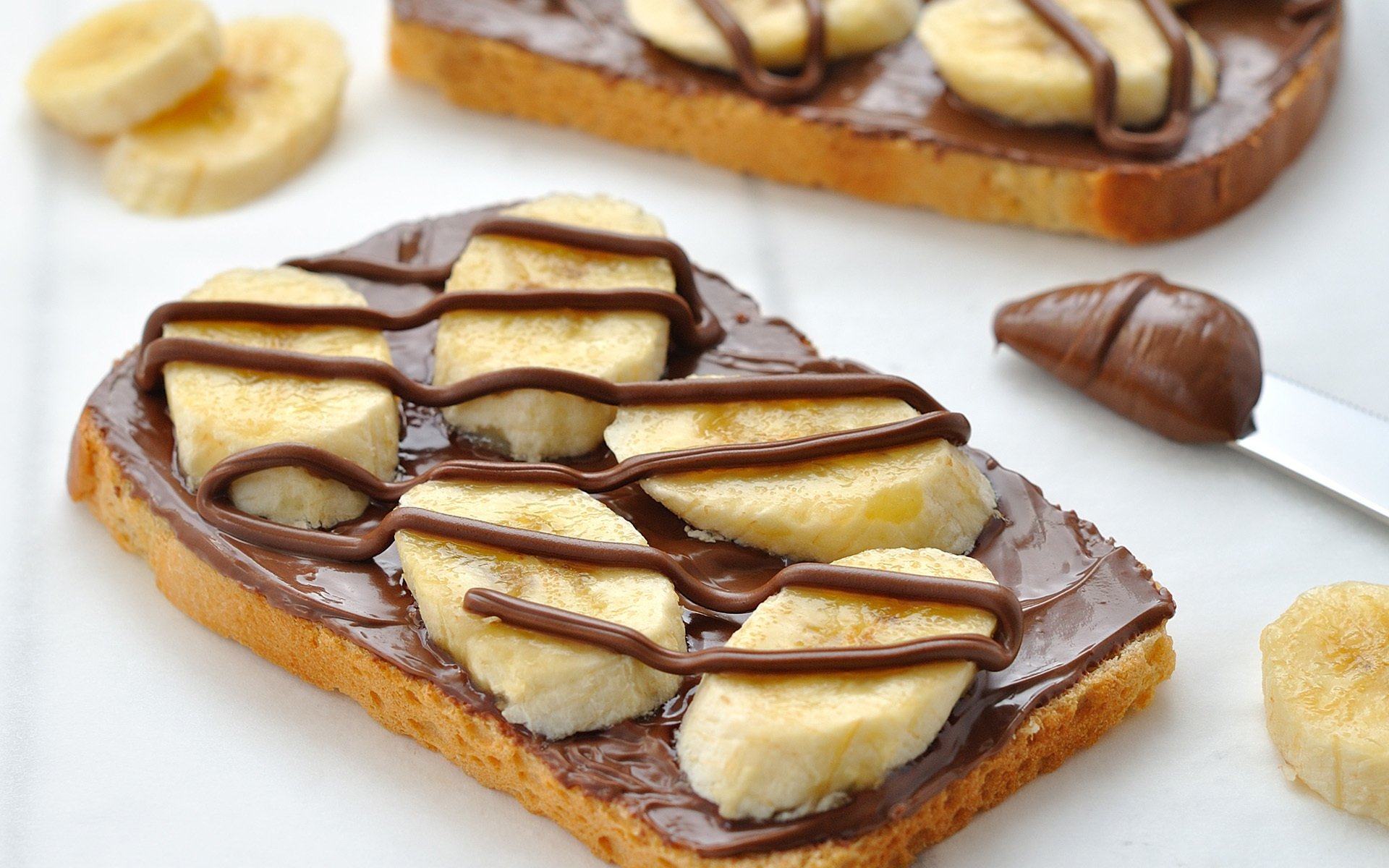 HD PC desktop wallpaper featuring a close-up of a sandwich with sliced bananas and chocolate spread drizzled on top.