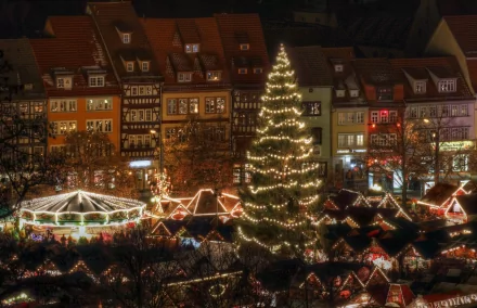 HD PC desktop wallpaper and background: man-made Christmas market at night with a tall lit tree, rows of illuminated stalls, a carousel and glowing historic buildings.