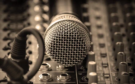 A close-up of a microphone on a sound mixing console, capturing the essence of music production. This high-definition image serves as a striking wallpaper backdrop.