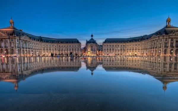 HD desktop wallpaper showcasing the man-made beauty of Place de la Bourse with its illuminated historic buildings reflected in the calm water at dusk.