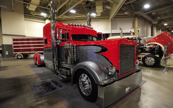 A high-resolution 4K Ultra HD desktop wallpaper featuring a classic red and black Peterbilt truck displayed indoors at a vehicle exhibition.