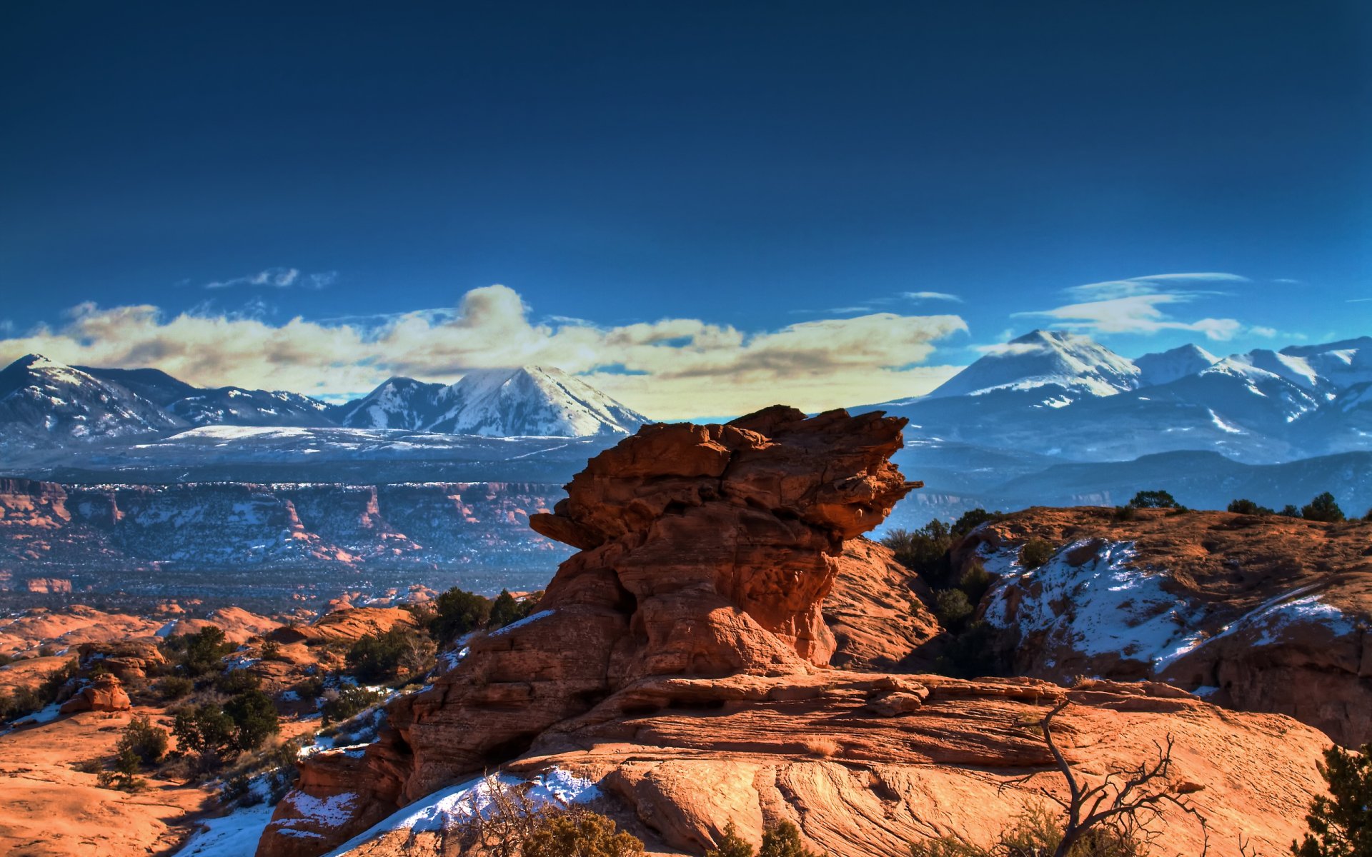 HDR landscape of Utah’s Moab desert featuring red rock formations and snow-dusted mountains under a vibrant blue sky, captured as an HD PC desktop wallpaper.