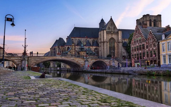 4K Ultra HD image of a man-made canal scene in Ghent, Belgium at sunset, featuring historic buildings and arched bridges along the water.