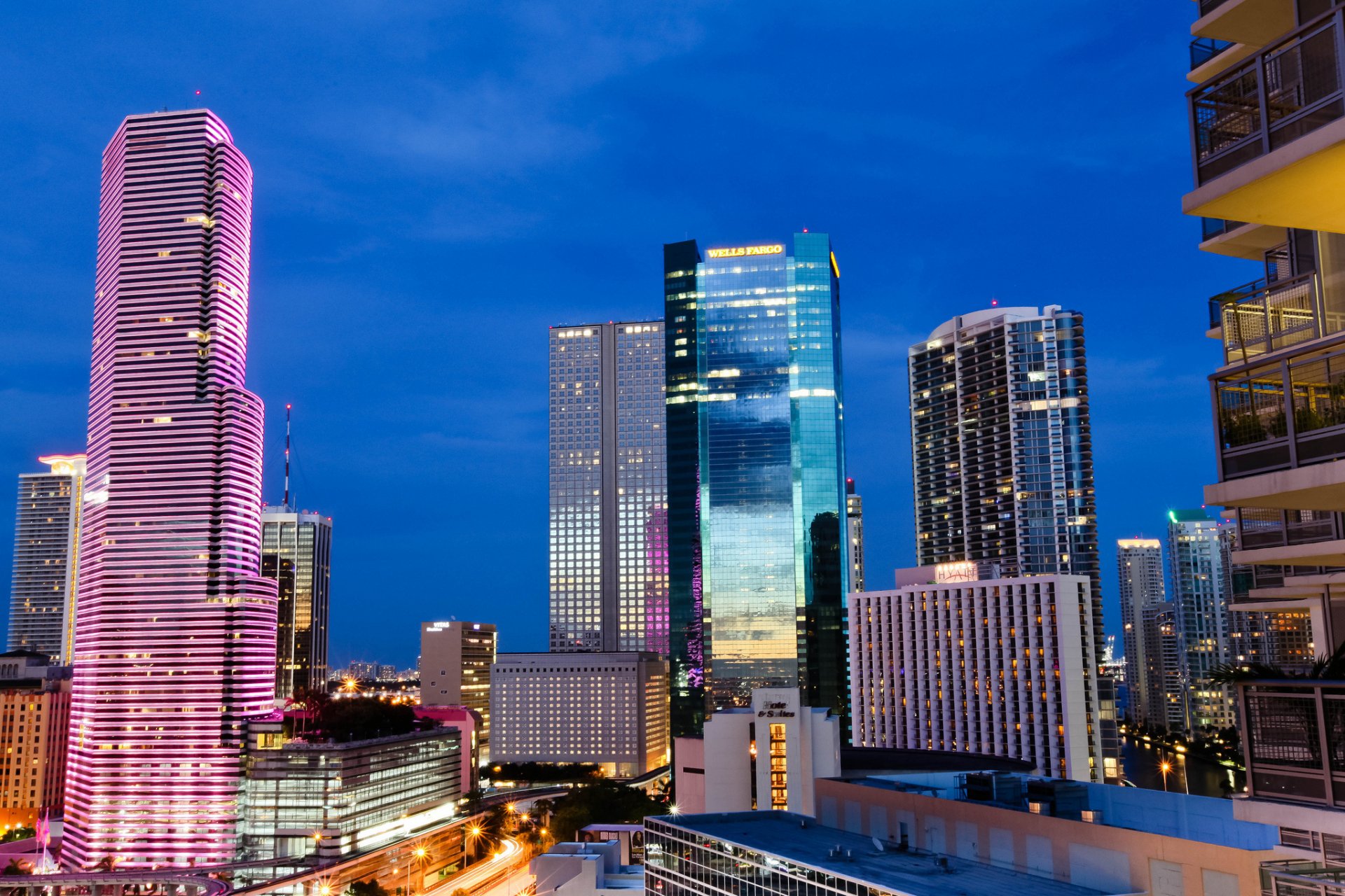 HD desktop wallpaper showcasing a vibrant Miami skyline at dusk with illuminated modern skyscrapers and urban architecture.