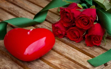 HD PC desktop wallpaper featuring a red heart-shaped candle and a bouquet of red roses on a wooden surface, celebrating Valentine's Day.