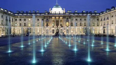 An elegant palace illuminated at dusk, with vibrant fountains casting a captivating glow on the surrounding area, creating a stunning HD desktop wallpaper background.