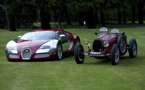 HD PC desktop wallpaper/background: glossy red Bugatti Veyron parked beside a vintage Bugatti racer on a manicured green lawn with trees in the background.