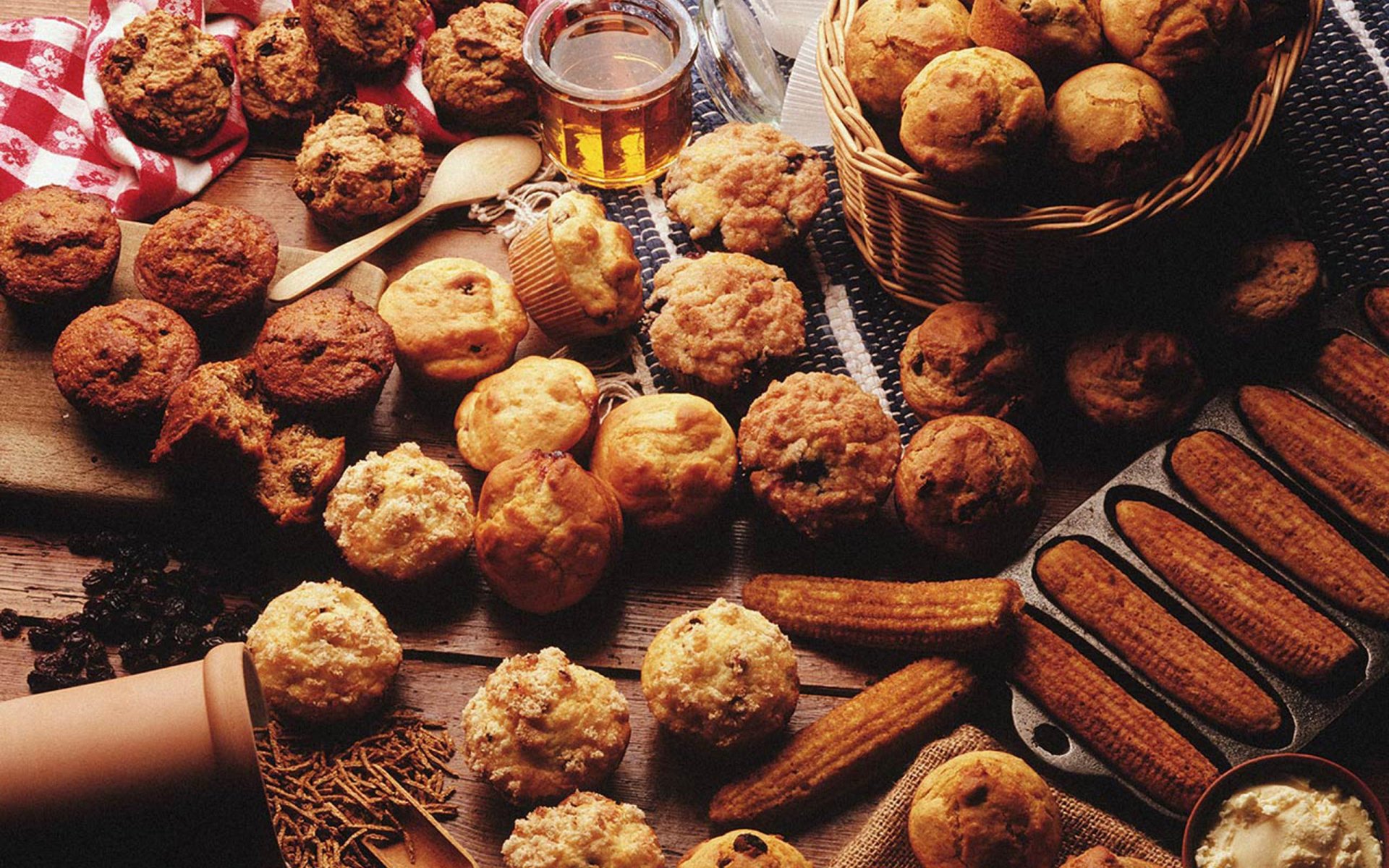 HD PC desktop wallpaper showcasing an assortment of freshly baked muffins, cookies, and bread with a jar of honey, highlighting warm tones and a cozy baking theme.