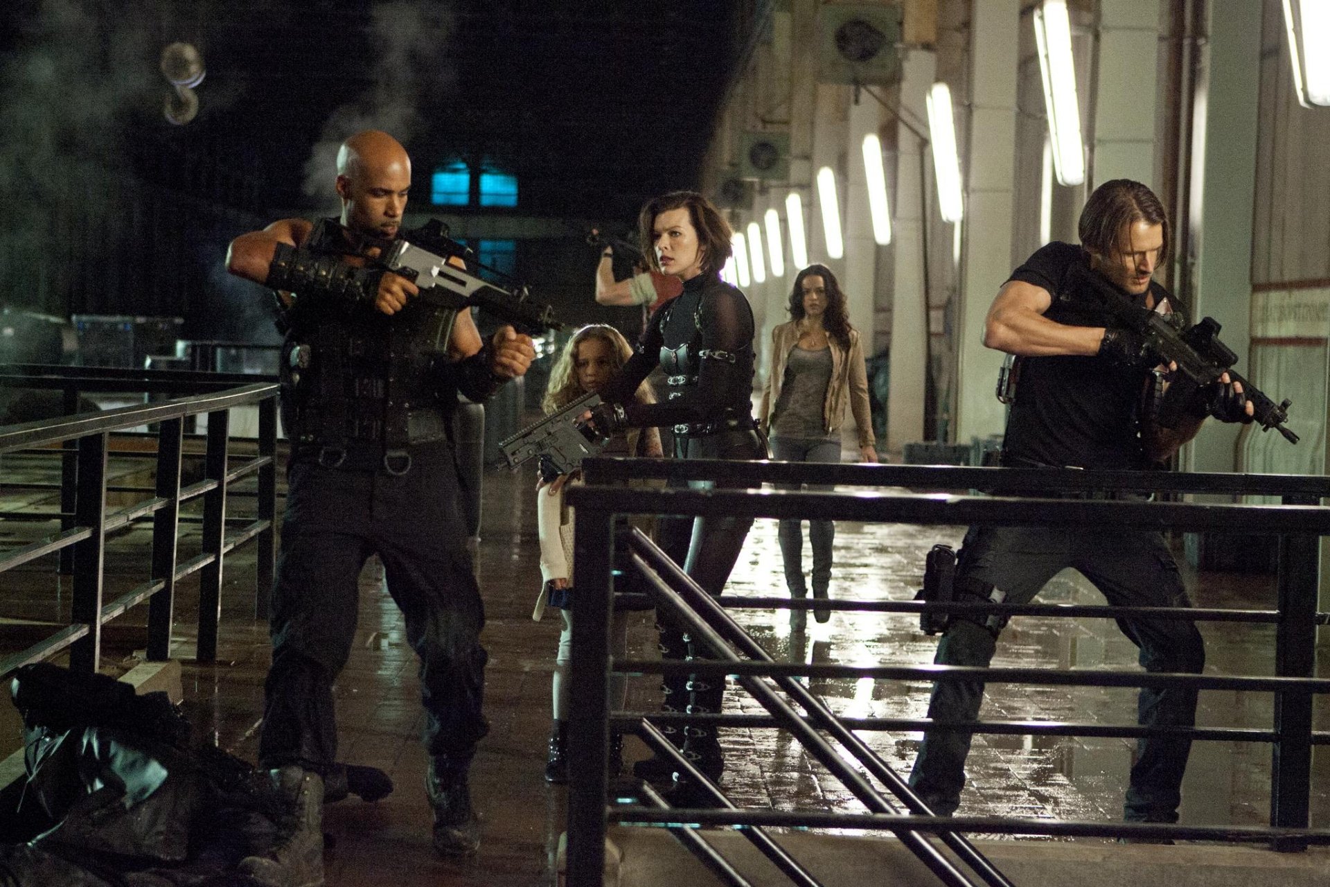 HD PC desktop wallpaper featuring an intense action scene from the movie Resident Evil: Retribution with armed characters in a dimly lit industrial setting.