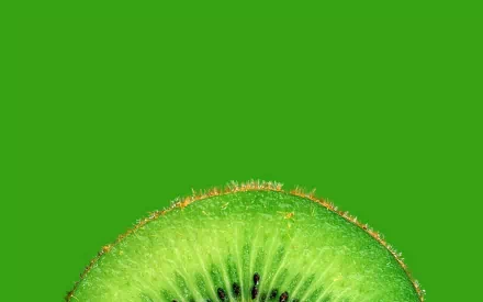 Close-up of a vibrant kiwi slice against a solid green background, showcased as an HD PC desktop wallpaper with a fresh and natural food theme.