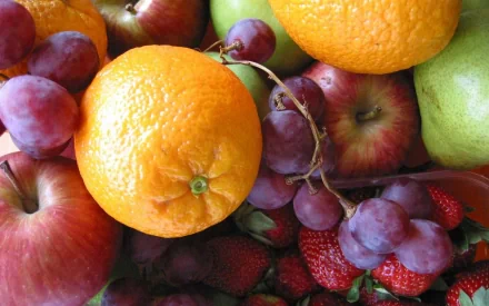 HD PC desktop wallpaper featuring a vibrant assortment of fresh fruits including oranges, apples, grapes, strawberries, and pears in a colorful, close-up composition.