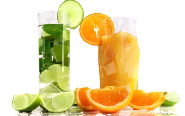 HD PC desktop wallpaper featuring refreshing citrus drinks, including a green lime cocktail and an orange juice glass, with fresh lime and orange slices.