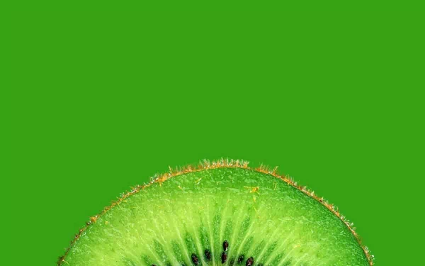 Close-up of a vibrant kiwi slice against a solid green background, showcased as an HD PC desktop wallpaper with a fresh and natural food theme.