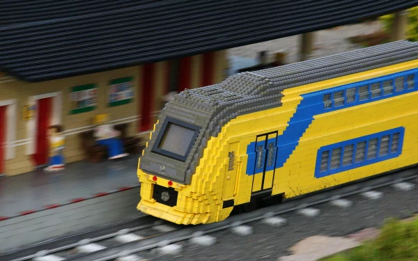 4K Ultra HD PC desktop wallpaper background showing a man-made LEGO yellow and blue passenger train model arriving at a station platform.