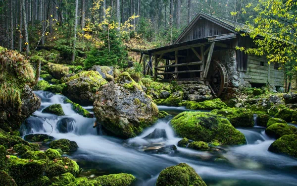 4K Ultra HD PC desktop wallpaper: moss-covered forest stream flowing past a man-made wooden watermill, a rustic cabin and wheel nestled among rocks and trees.
