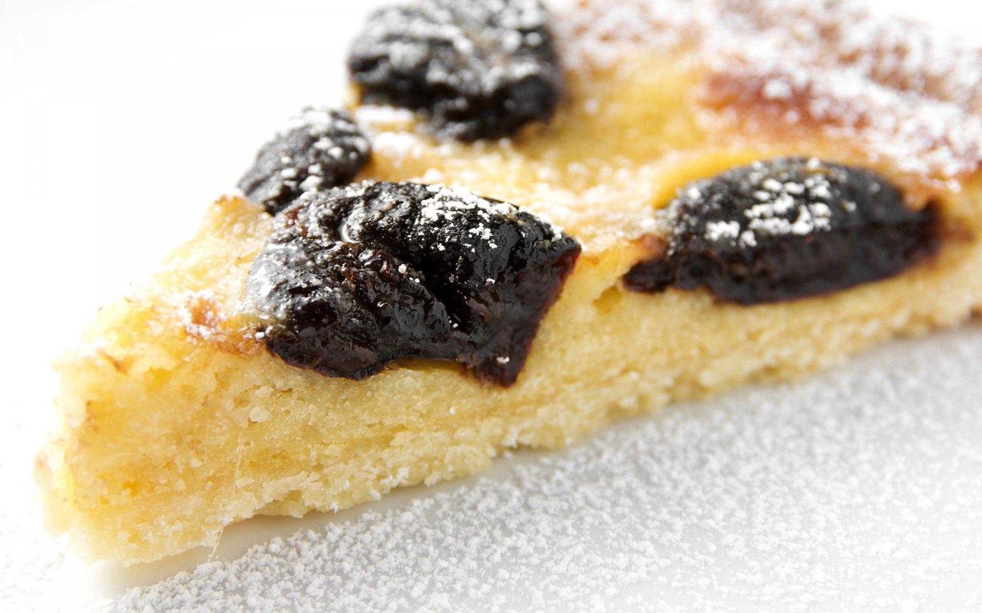 Close-up of a baked tart slice with dark fruit pieces and powdered sugar, captured in HD for a PC desktop wallpaper background.