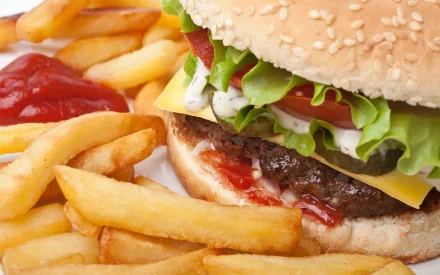 HD PC desktop wallpaper featuring a close-up of a cheeseburger with lettuce, tomato, and ketchup alongside golden French fries and a dollop of ketchup.