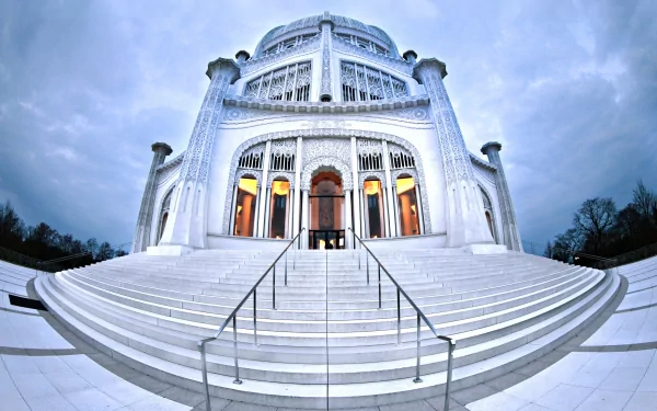 HD desktop wallpaper of the majestic Bahá'í Temple, showcasing its intricate architecture and grand white marble steps under a cloudy sky.