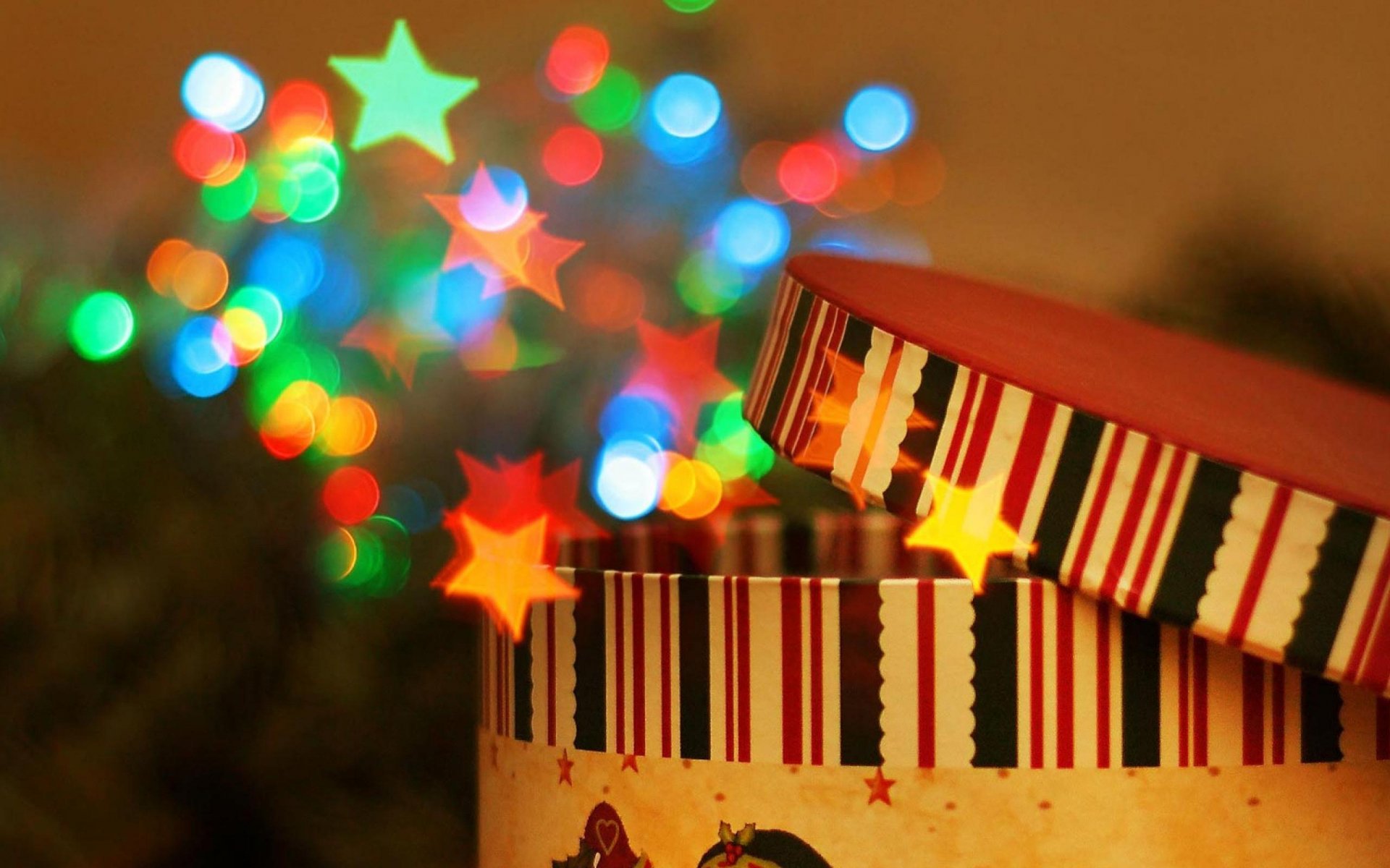 HD PC desktop wallpaper featuring a festive gift box with striped lid and colorful star-shaped bokeh lights in the background.
