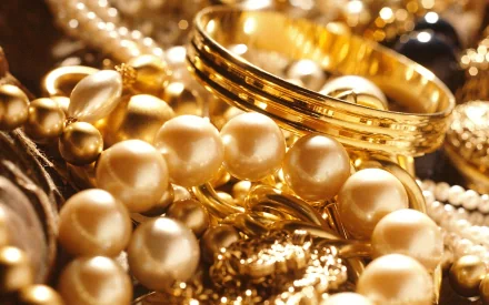 Close-up HD desktop wallpaper of man-made gold jewelry featuring pearls, rings, and intricate details in a warm, luxurious setting.