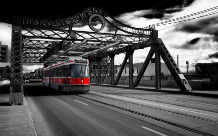 HD desktop wallpaper showing a red tram crossing an old steel bridge in a black-and-white urban setting with dramatic clouds.