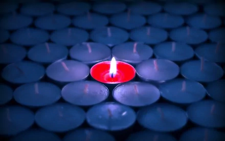 HD desktop wallpaper featuring a single lit red candle surrounded by numerous unlit blue candles, captured in detailed photography.