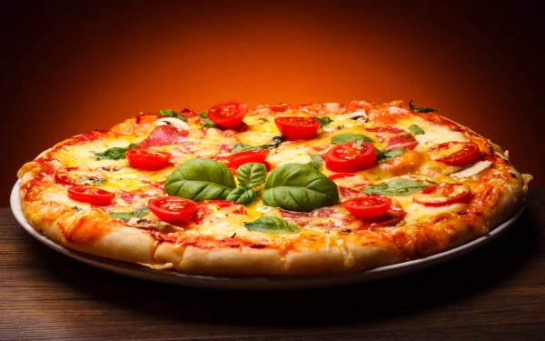 A delicious pizza topped with fresh tomatoes and basil on a wooden surface, set against a warm, glowing background. A vibrant HD wallpaper for food lovers.
