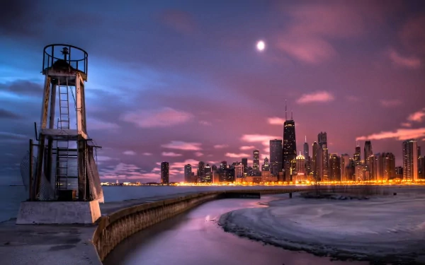 A stunning view of the Chicago skyline at dusk, featuring a lighthouse on the shoreline, with vibrant colors reflecting in the water. This HD wallpaper captures the essence of man-made beauty in Illinois.