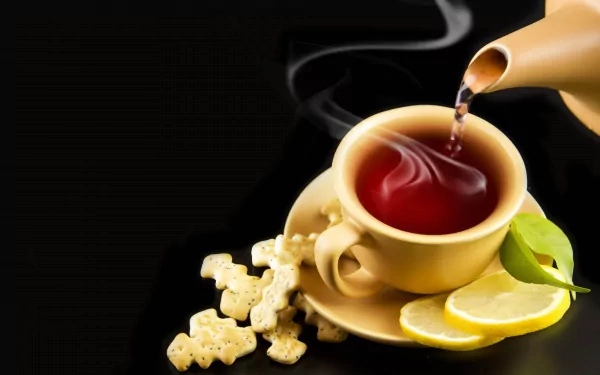 A steaming cup of tea is poured from a teapot into a yellow cup with lemon slices and sugar cubes nearby, captured in 4K Ultra HD for a vivid PC desktop wallpaper.
