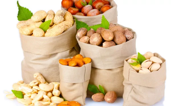 A collection of various nuts displayed in paper bags, with some nuts scattered around. This vibrant image serves as a 4K Ultra HD PC desktop wallpaper and background.