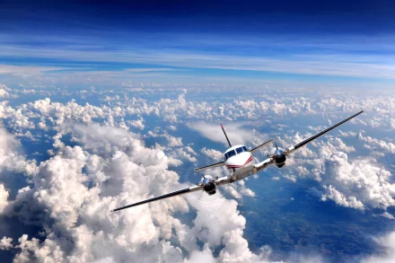 A high-definition wallpaper features an aircraft soaring through a bright blue sky, surrounded by billowing white clouds, creating an expansive and dynamic background.