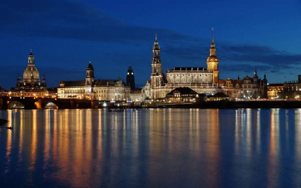 Nighttime view of Dresden's illuminated skyline in Germany, reflected on the calm river waters, captured as an HD desktop wallpaper background.