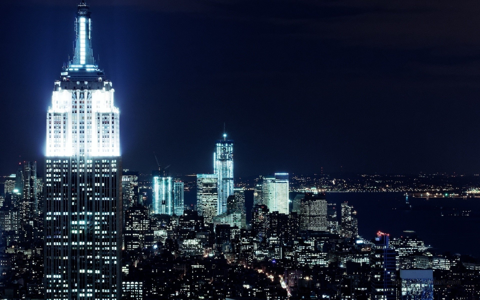 Nighttime view of the illuminated Empire State Building against the New York City skyline, captured in a high-definition desktop wallpaper.
