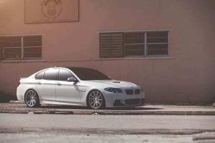 A sleek white BMW sedan parked beside a building, showcasing its stylish design and modern features, serves as an attractive HD PC desktop wallpaper and background.