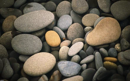 HD desktop wallpaper featuring a close-up of smooth, rounded stones in natural tones with subtle lighting, highlighting their textures in a serene nature setting.
