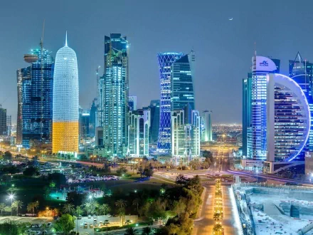 A stunning HD wallpaper and background showing the vibrant, illuminated skyline of Doha, featuring modern high-rise buildings at night.