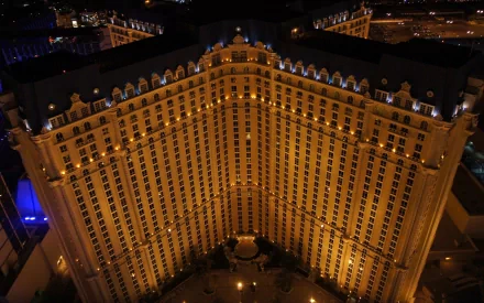 A stunning aerial view of the Paris Las Vegas hotel, showcasing its iconic architecture illuminated at night, surrounded by the vibrant energy of the Las Vegas Strip.